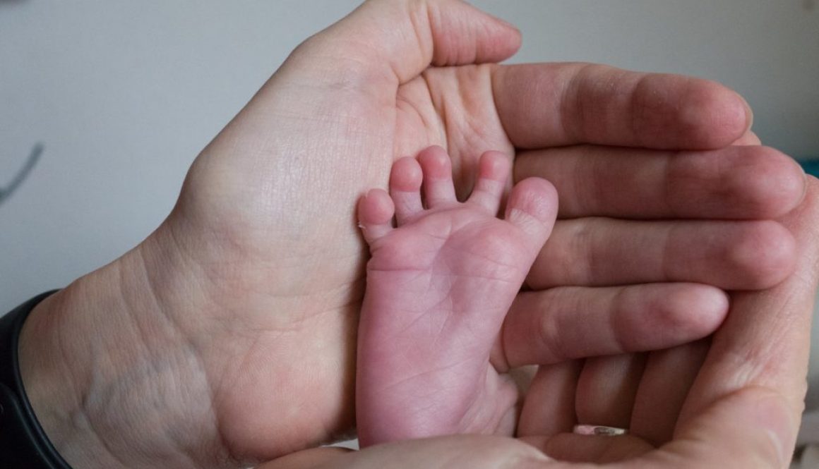detská nožička 8 dňového bábätka v dlaniach matky - barefoot love