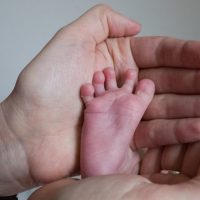 detská nožička 8 dňového bábätka v dlaniach matky - barefoot love